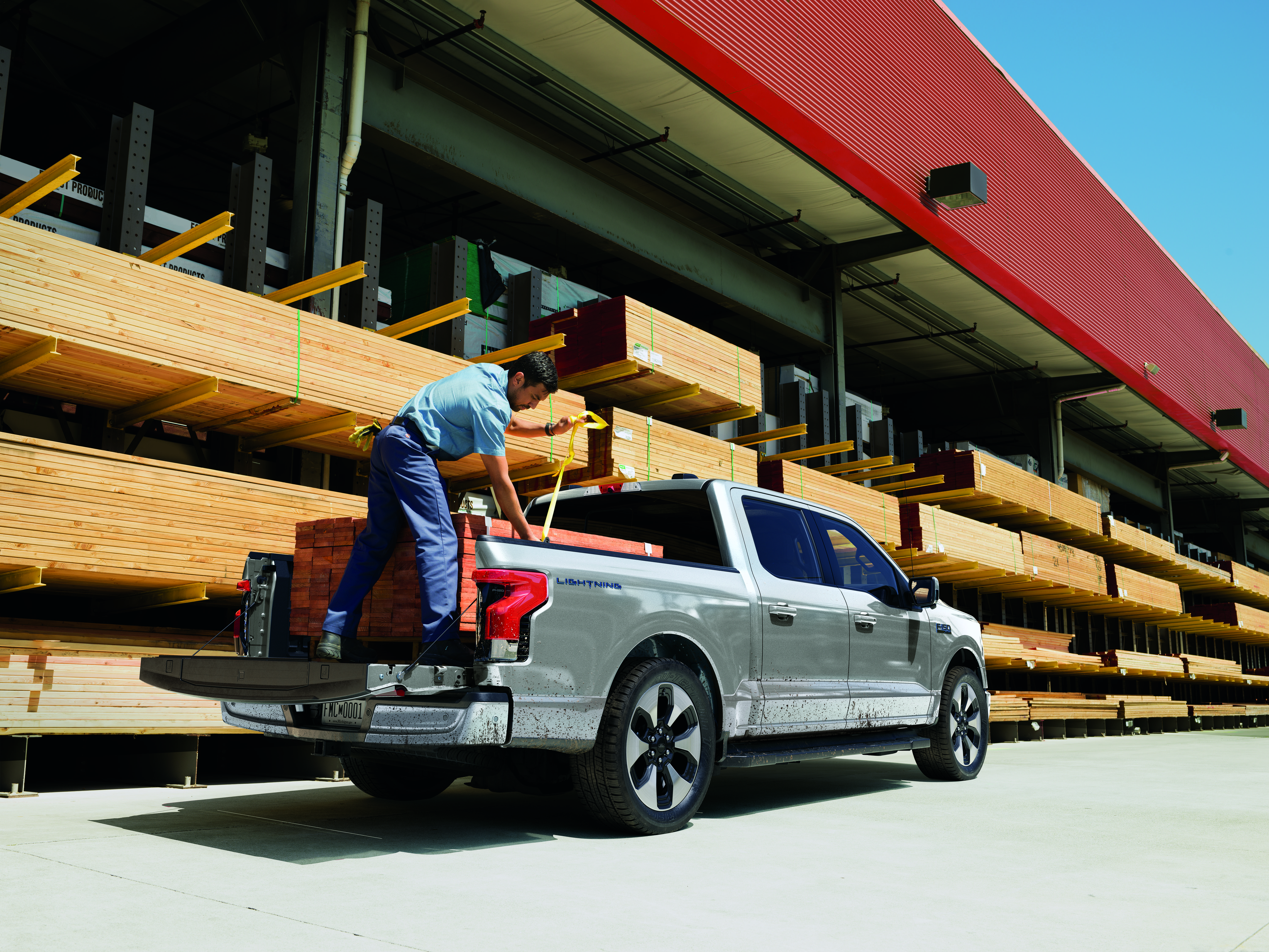 A man loads wood into the bed of a truck.